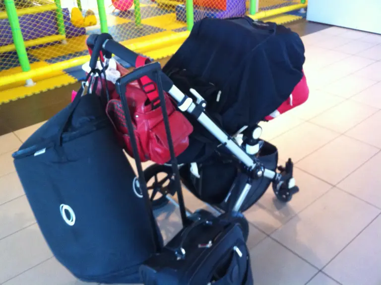 hand luggage and stroller at the airport with stroller travel bag abnd snoozeshade sleep cover over it.